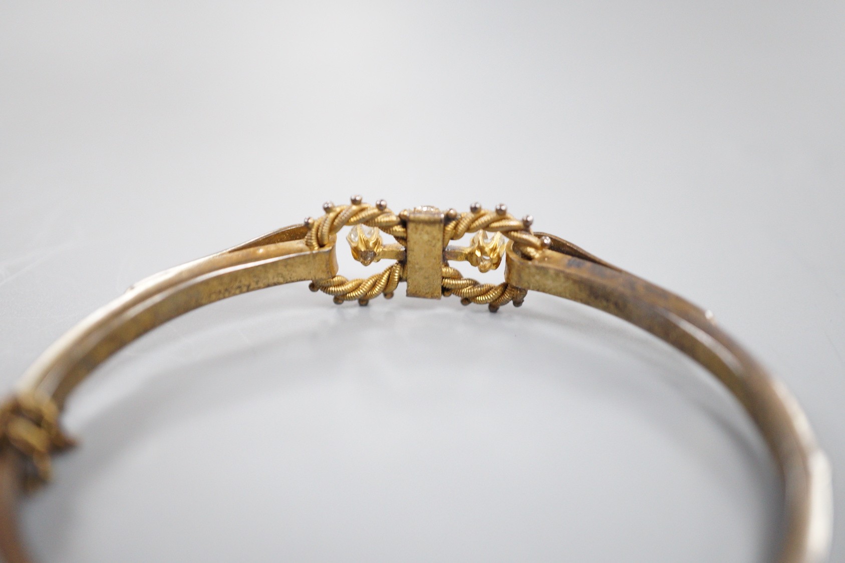 A late Victorian yellow metal, six stone diamond cluster set hinged bangle, with split pearl set shoulders, interior diameter 56mm, gross weight 10.5 grams.